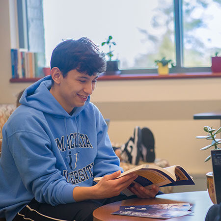 Young man sitting at desk reading book